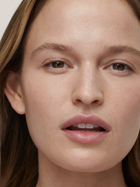 Woman with lips slightly parted with hair tucked behind one ear