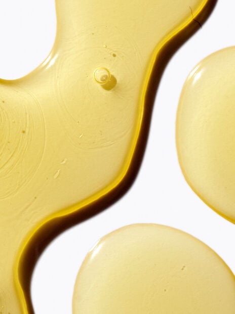 Close up of three groups of yellow liquid on white background