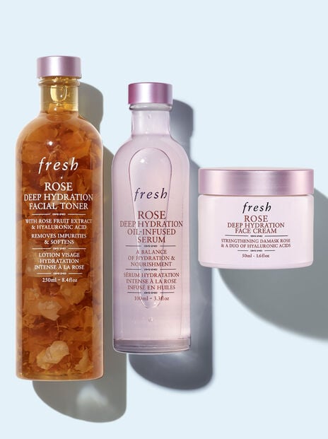 Lineup of Fresh Rose Toner, Serum and Face Cream against light blue background