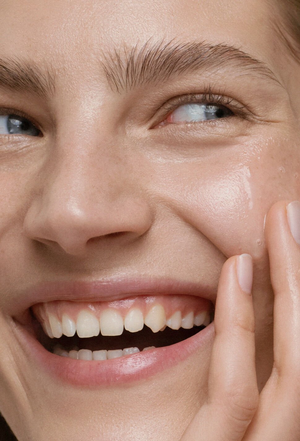 Woman smiling with mouth open and hand on her left cheek