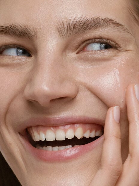 Woman smiling with mouth open and hand on her left cheek