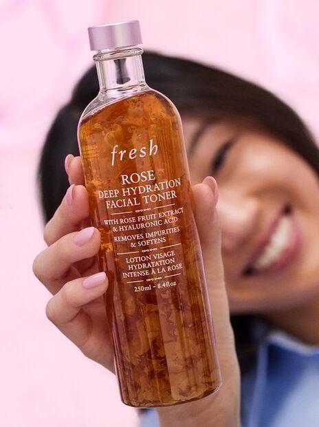 Close up of a smiling woman holding Rose Toner