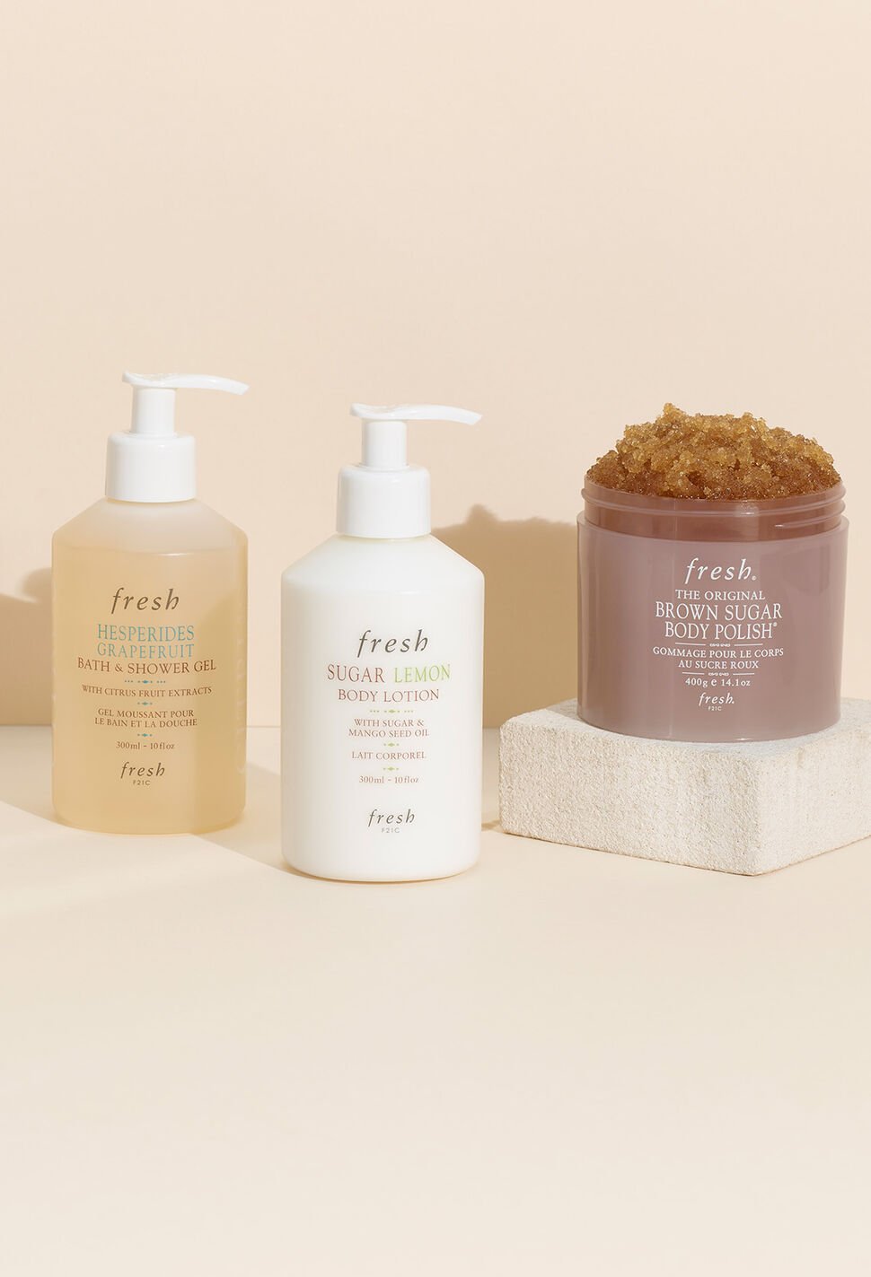 Fresh Body Wash, Lotion and Brown Sugar Body Scrub against a peach colored background