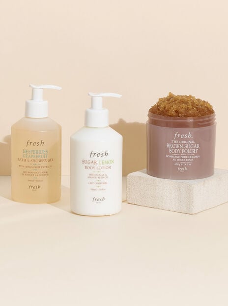 Fresh Body Wash, Lotion and Brown Sugar Body Scrub against a peach colored background